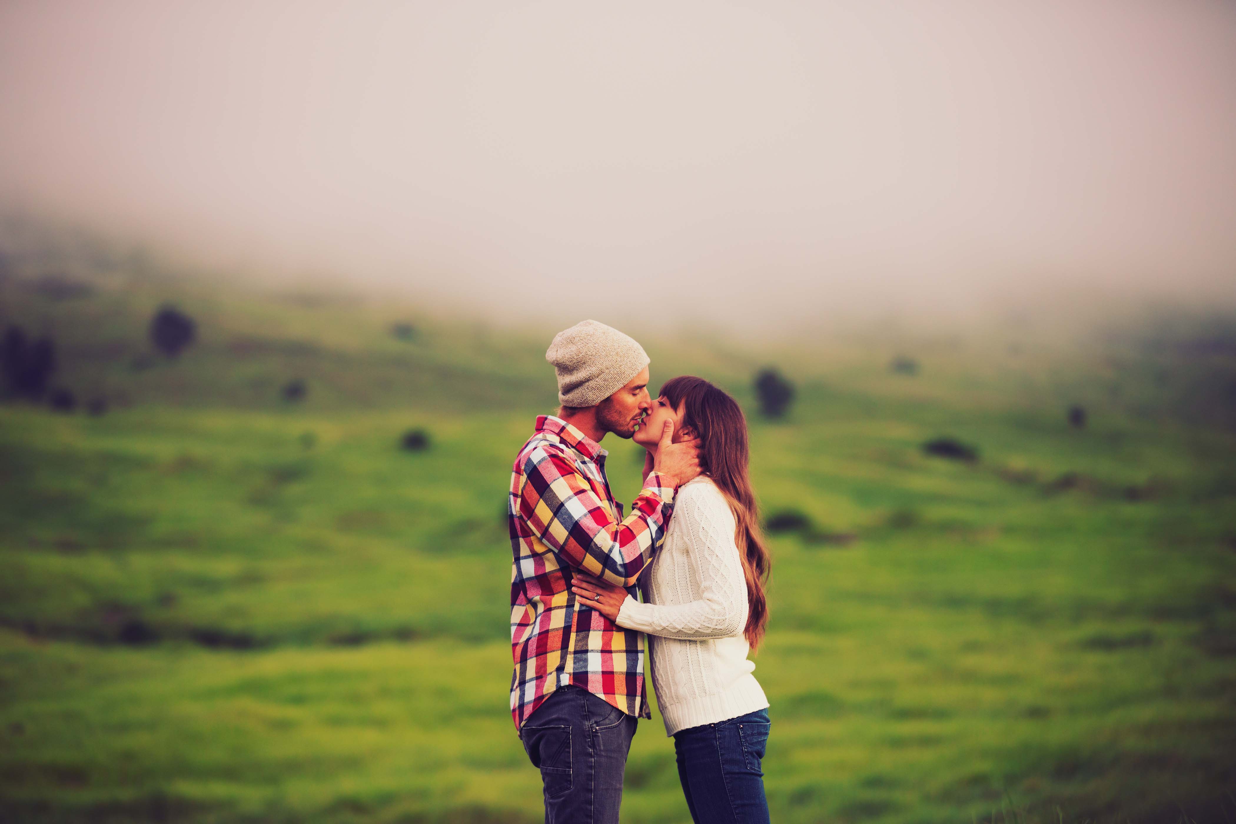 couple kissing, plaid shirt, beany, winter hat, white sweater, white jumper, cute couple, field, countryside, kissing in field, couple stealing a kiss, private moment, ireland, scotland, green pasture,