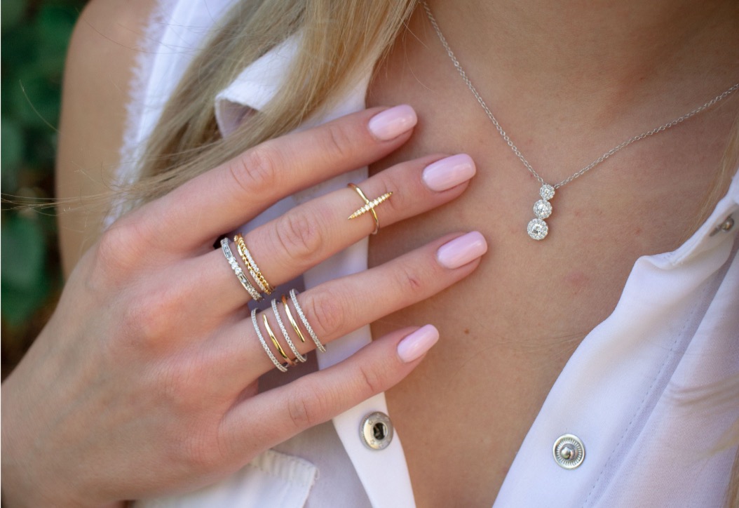 Woman wearing diamond pendant, stackable rings, and sterling silver bracelet