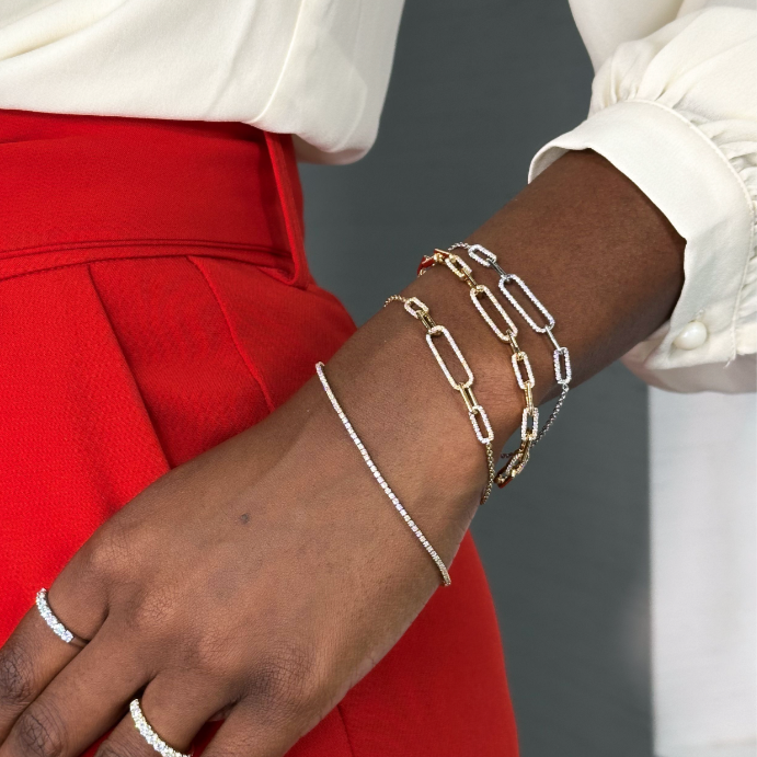 black woman's wrist with layered diamond paperclip bracelets and tennis bracelet