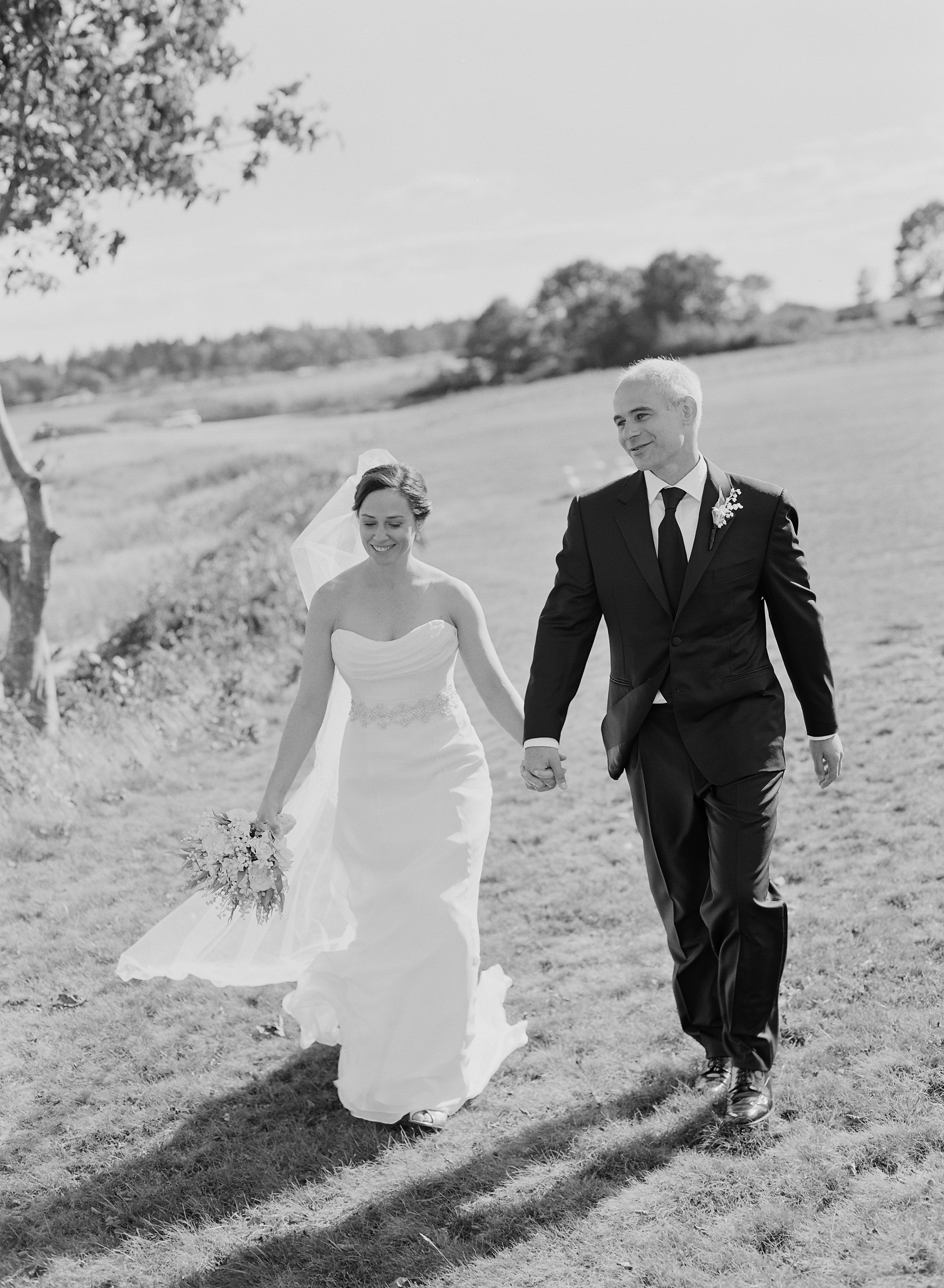happy couple, bride and groom, outdoor wedding, lakeside wedding, lakefront wedding pictures, bride, groom, wedding dress, black and white wedding photo, smiling couple, couple holding hands
