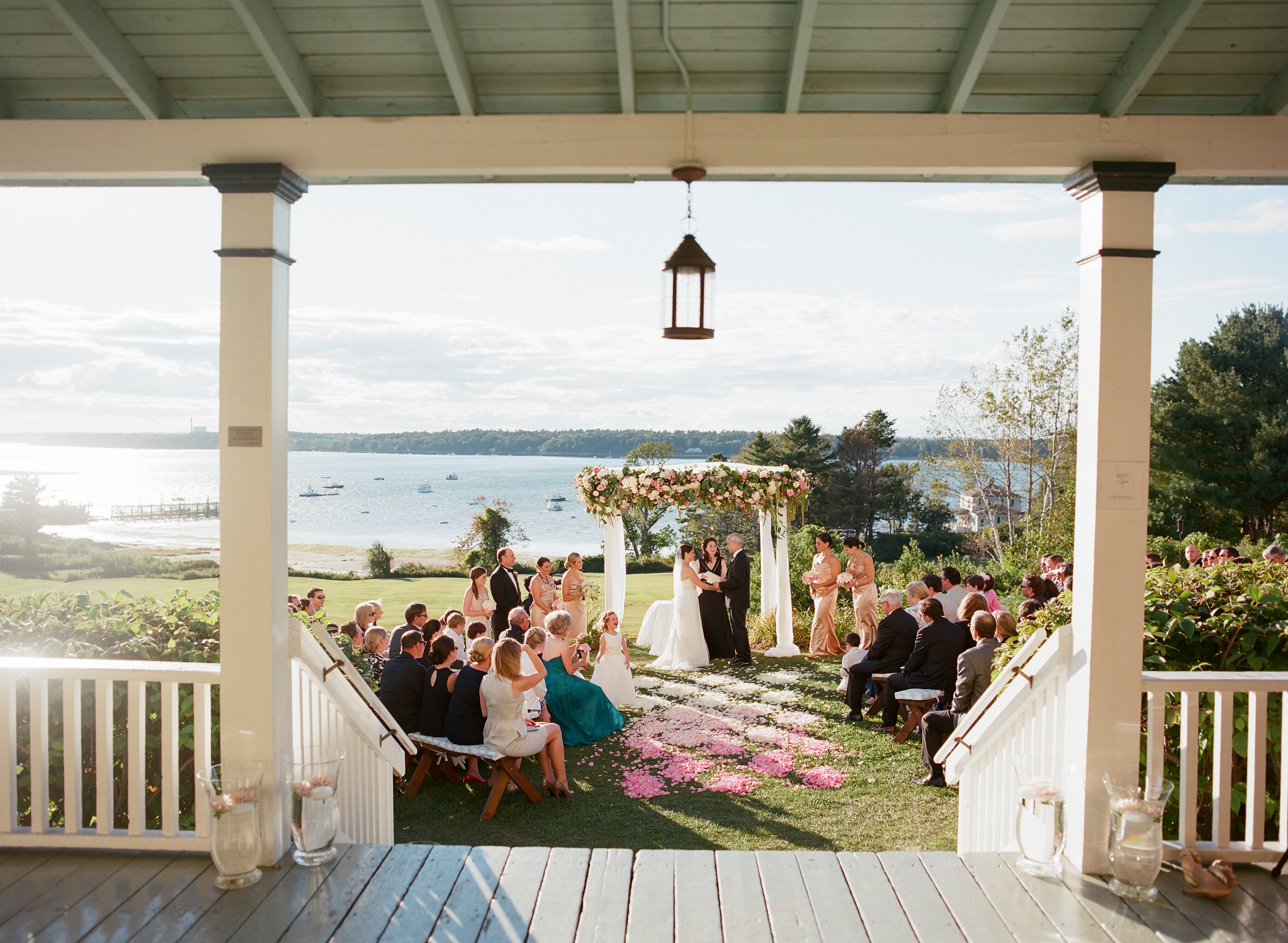 waterfront wedding, lakeside wedding, midwest wedding, small ceremony, outdoor wedding, pink flower wedding decor, lakeside wedding decor, summer wedding, southern wedding, porch, lantern, lake, wedding guests, arbor, wedding vows, pier, boats, glass pitchers, glass vases, wooden porch, painted porch