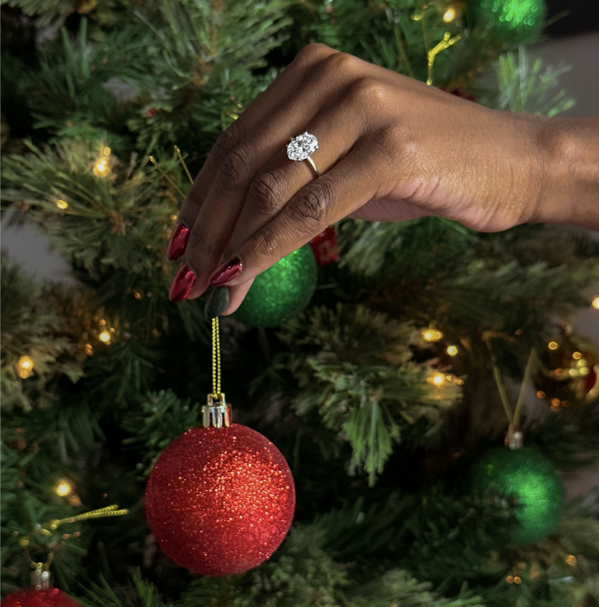 woman with oval diamond engagement ring holding Christmas ornament