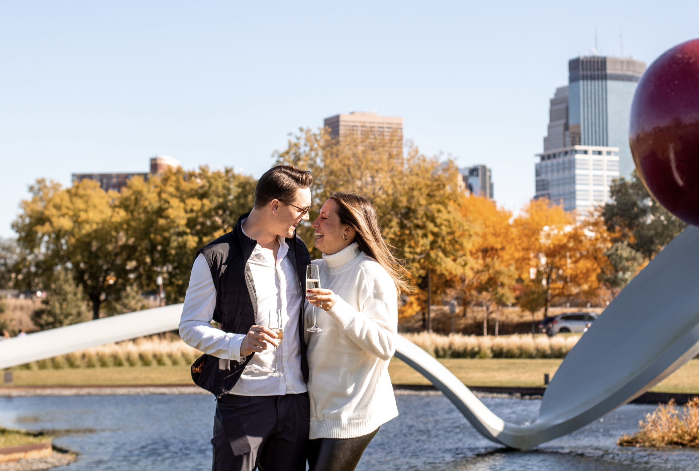couple with champagne in front of Minneapolis Spoon Cherry sculpture